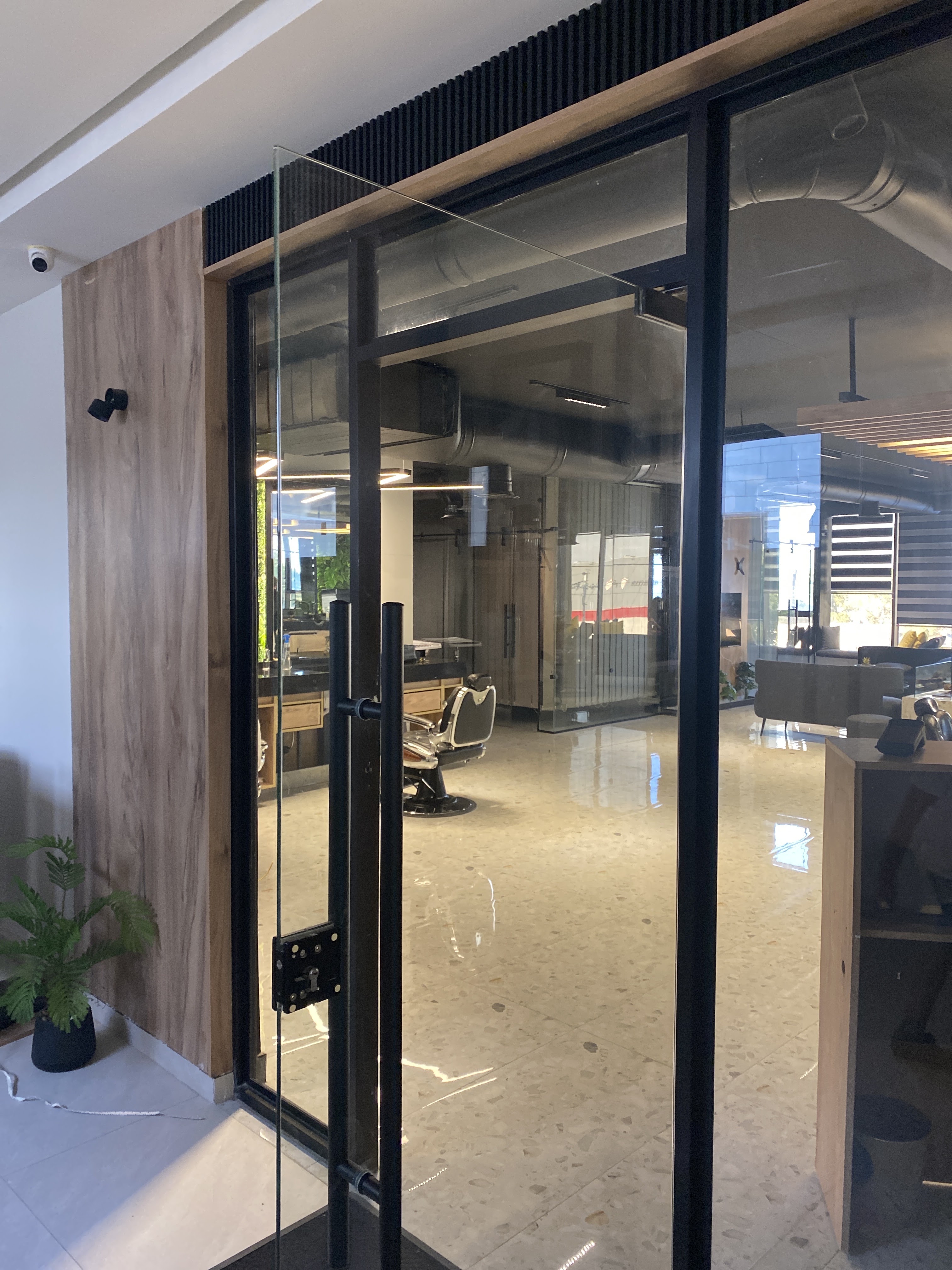 Glass entrance door looking into the salon with a barber chair and terrazzo floor